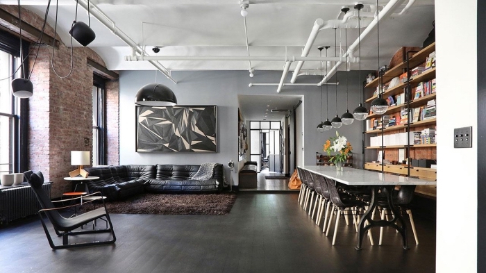 meuble style industriel dans un salon gris, modèle de canapé en cuir noir, éclairage industriel sur rail en blanc mate 