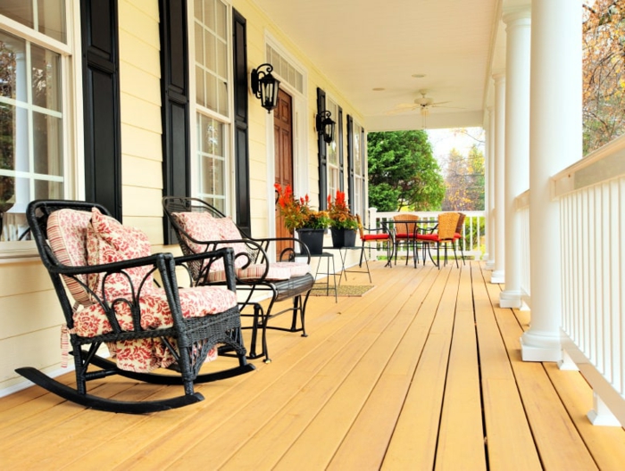 chaises de relaxation sur une terrasse en bois, grande véranda ouverte en bois et blanc, rambarde blanche