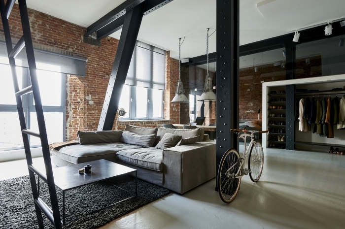 agencement espace loft industriel aux murs briques rouges avec meuble style industriel, modèle de canapé d'angle