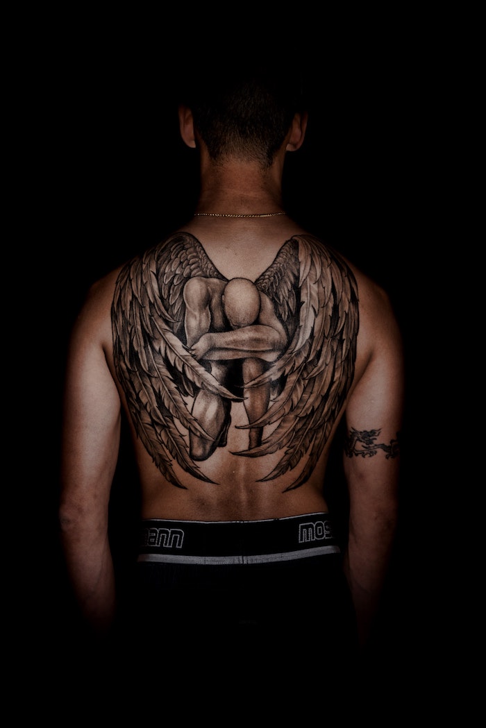 Dos entierement tatoué avec un ange sur son genou, motif tatouage, ange dessin tatouage original, dos encre dessin sur la peau ange