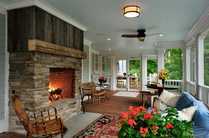 décorer sa terrasse et amenager une veranda chaleureuse, grande cheminée en pierre sofa bleu, plantes fleuries