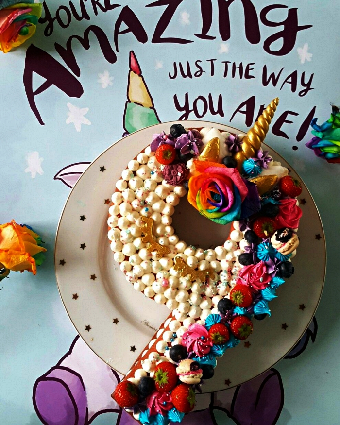 gateau anniversaire enfant sur le thème licorne, gâteau en forme de chiffre garni de meringues en buttercream, fraises et meringues croquantes colorées