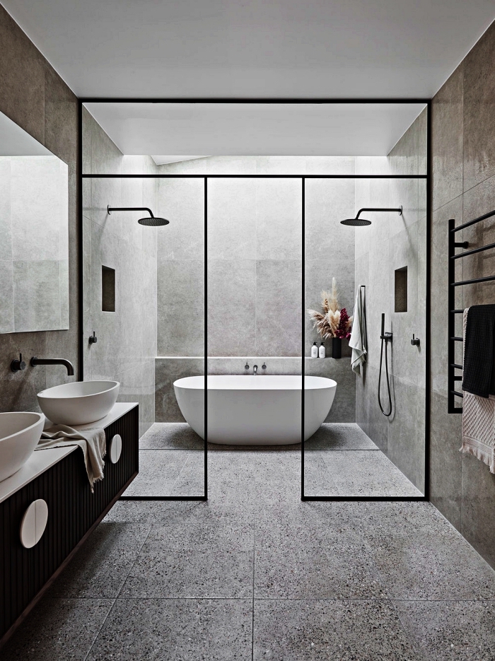 salle de bain contemporaine en carreaux effet ciment avec douches et baignoire îlot délimitées par une verrière 