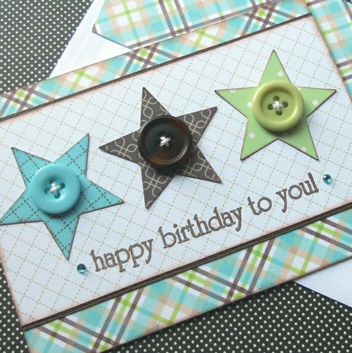 une carte d'anniversaire scrapbooking en papier à motifs carreaux décorée d'étoiles en papier et de boutons