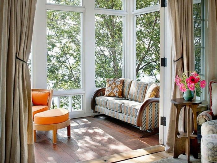 petite veranda sympathique, chaise orange, grandes fenêtres blanches, table haute, vase turquoise
