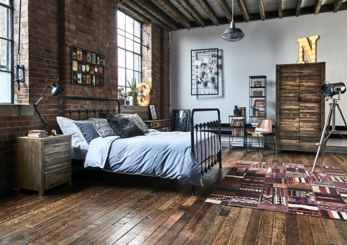 deco industrielle dans une chambre aux murs briques avec plancher bois foncé, modèle de lit industriel en fer forgé