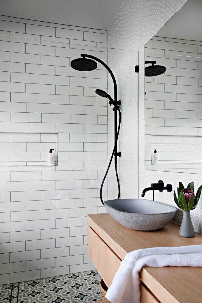 une salle de bain contemporaine au design scandinave épuré avec colonne de douche noir mat et vasque à poser en ciment, des carreaux de ciment au sol pour une touche vintage chic dans la salle de bain