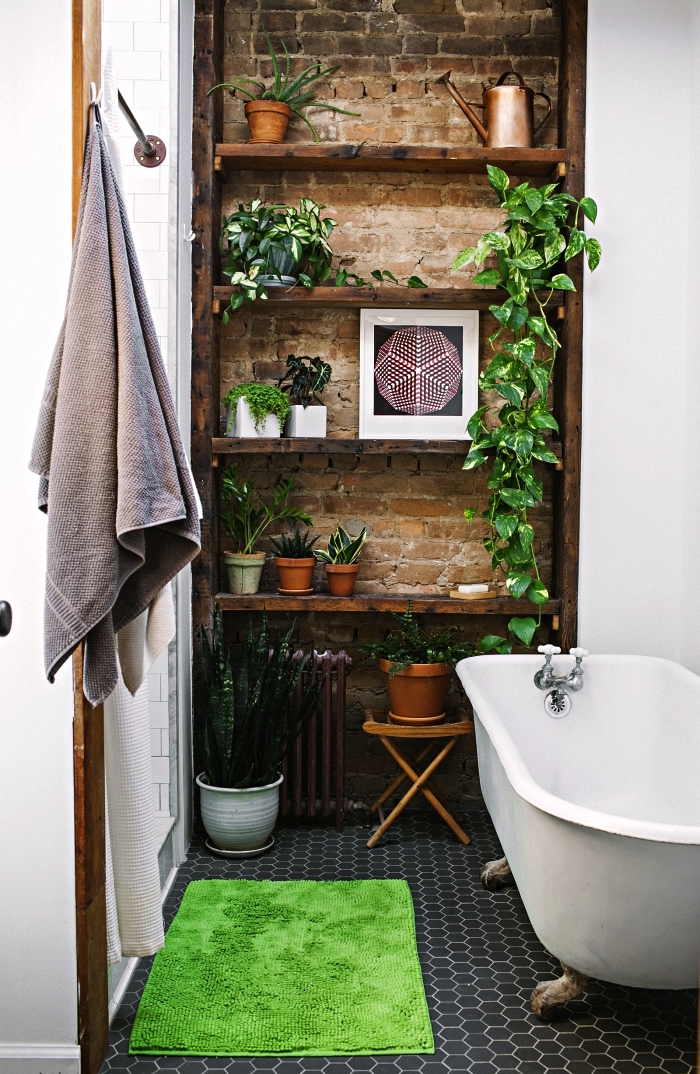 aménagement petite salle de bain avec baignoire sur pieds vintage et une déco de plantes vertes, pan de mur en briques avec des étagères ouvertes aux accents bohèmes chic