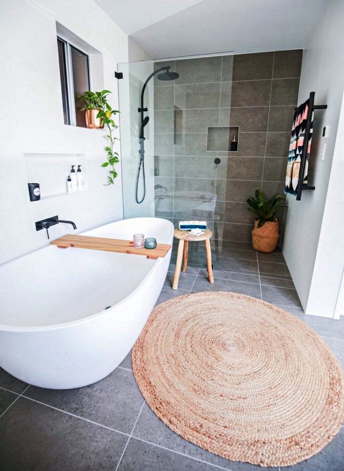 une salle de bain gris et blanc avec une baignoire zen dotée d'un pont de baignoire et une douche italienne délimitée par une paroi discrète en verre