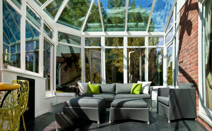 fauteuils gris, coussins verts, sol en grandes dalles grises, toiture et murs vitrés, veranda photo
