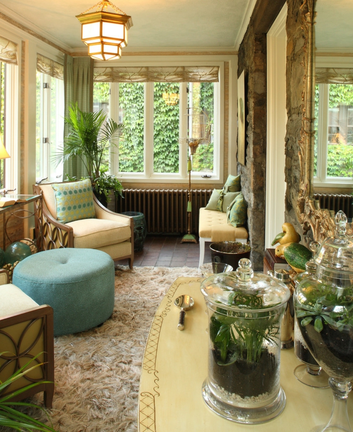 joli amenagement de veranda, tabouret turquoise, tapis oriental, fauteuil beige, grande bonbonnière
