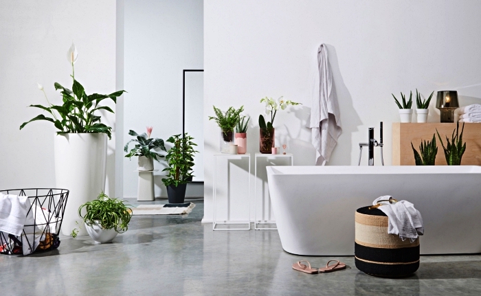 salle de bain blanche aux accents végétaux avec baignoire îlot au design moderne, des accessoires de salle de bain de style scandinave et ethnique chic