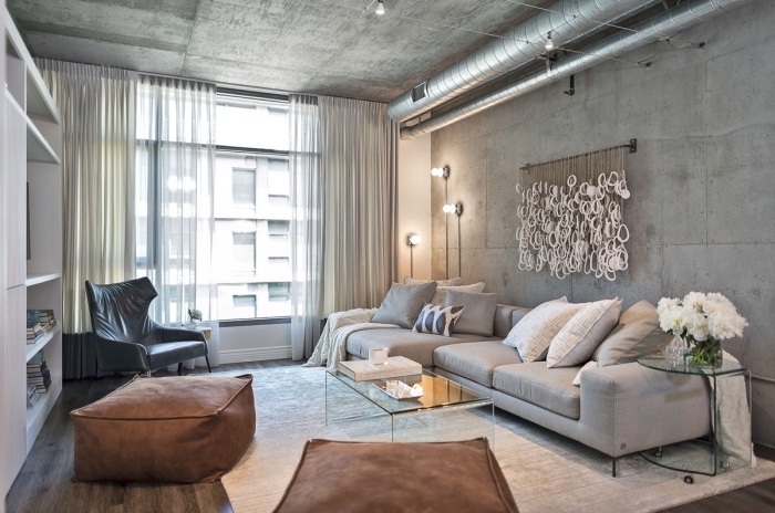 déco de salon industriel au plafond et murs béton avec parquet bois foncé, modèle de canapé en gris clair avec coussins blancs et gris
