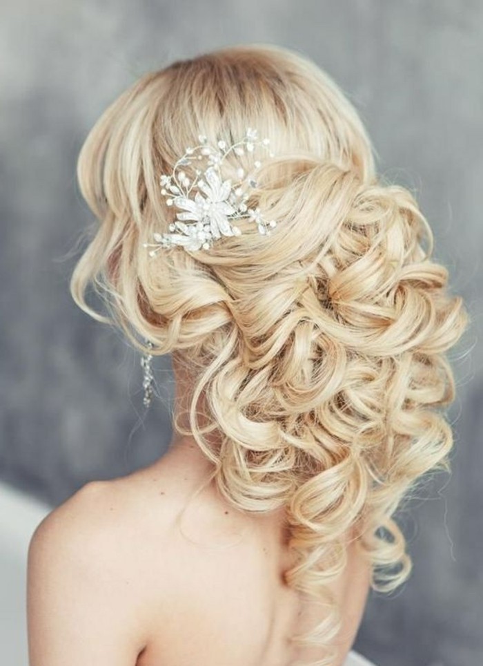 exemple coiffure mariage avec volume en arrière et boucles attachées et accessoirisées d une fleur blanche