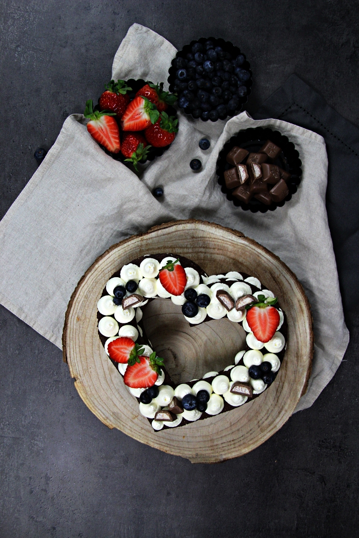 gateau coeur au chocolat en pâte sablée, gâteau en forme de coeur garni de meringues en buttercream déposé sur un rondin de bois