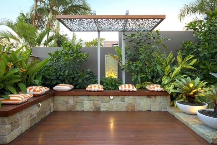 comment décorer espace extérieur maison, exemple de terrasse en bois foncé avec banc en bois et plantes vertes