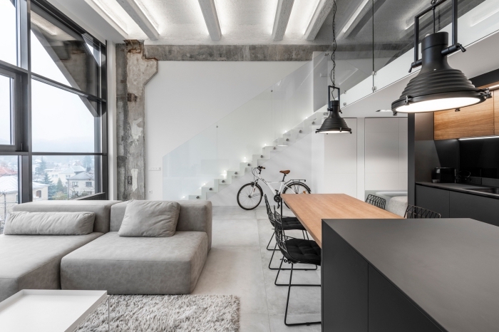 design contemporain dans un salon style industriel aux murs blancs avec plancher effet béton, modèle cuisine bois et gris anthracite