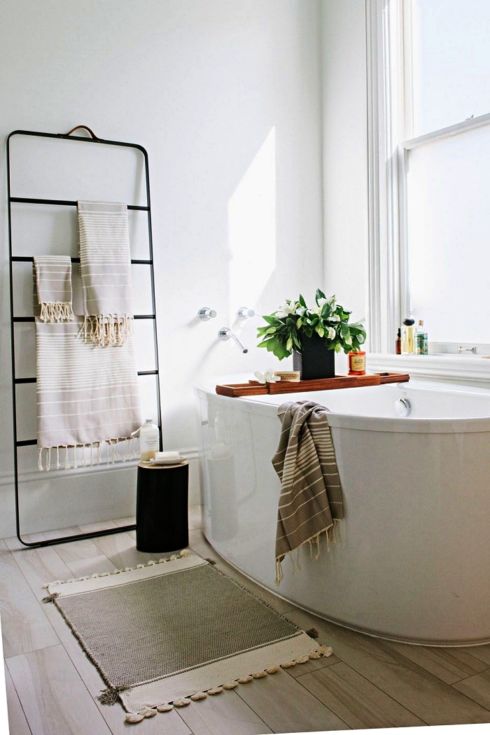 décoration de salle de bain nature avec baignoire îlot ovale et porte-serviette minimaliste en métal, revêtement de sol en parquet clair pour salle de bains