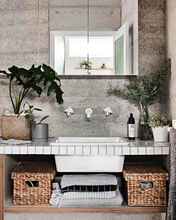 modele salle de bain d'ambiance zen et authentique d'aspect béton, meuble salle de bain avec plan vasque en carreaux blancs décoré de paniers en fibres naturelles