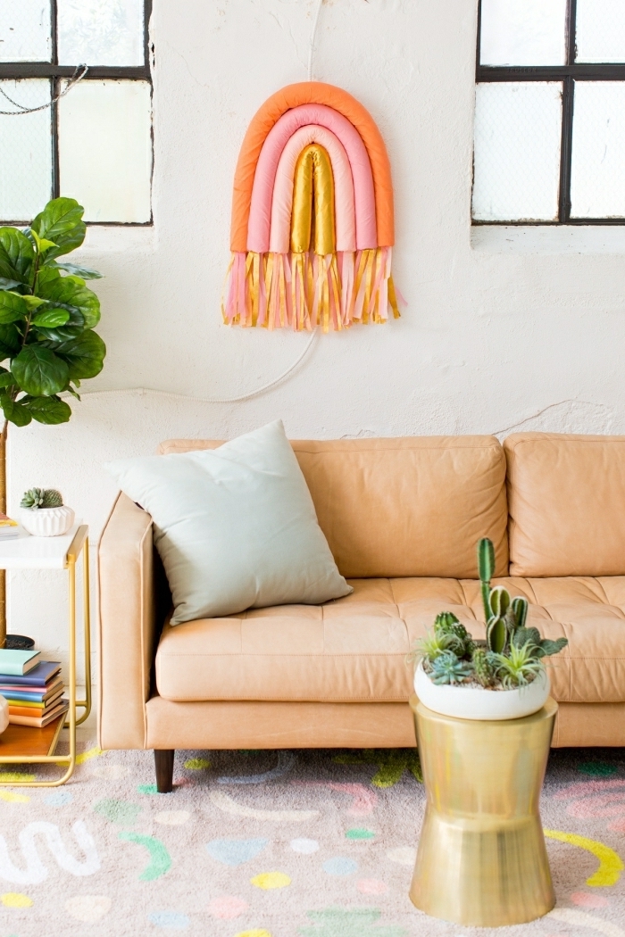 deco mural arc-en-ciel aux couleurs pastels, sofa orange pâle, grand pot de fleurs, coussin gris, table d'appoint