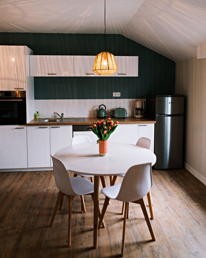 cuisine blanche de style scandinave, meuble cuisine blanc mis en relief par le mur vert foncé et le plan de travail bois