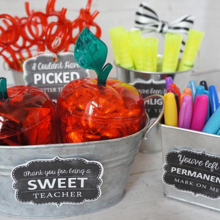 bacs à cadeaux avec des stylos rangés à l intérieur et de boites plastiques en forme de pomme avec bonbons à l intérieur