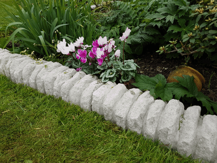 pierres blanches comme éléments de bordure de jardin, fleurs et plantes vertes, vieux pot 