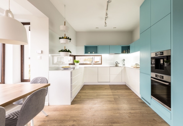 exemple agencement cuisine spacieuse avec fenêtres, revêtement plancher de cuisine en bois, modèle armoires de cuisine en bleu