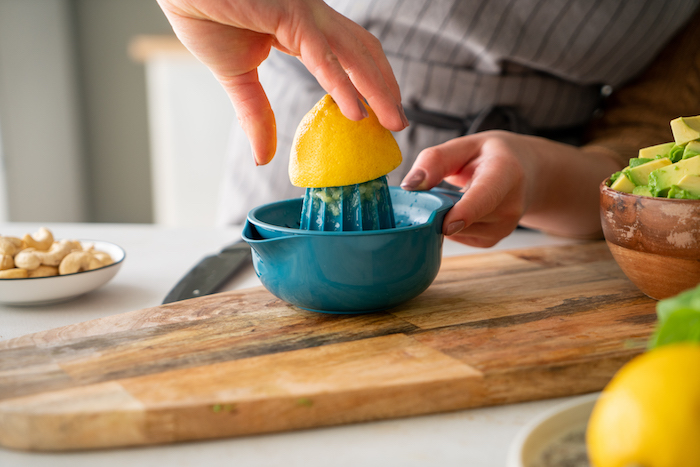 presser un citron à l aide de presse citron pour retirer le jus de citron, etape pour réaliser recette avocat en entrée pesto