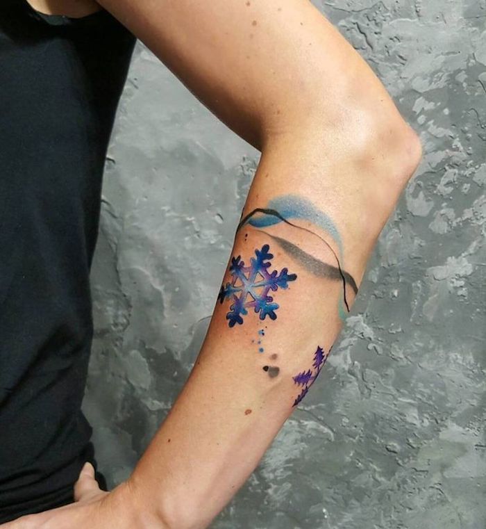 flacon de neige coloré bleue et violet sur le bras d une femme, tatouage hiver élégante et esthétique
