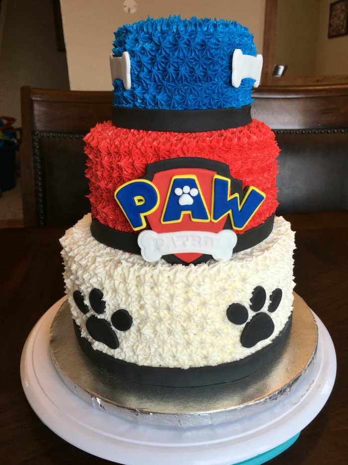 joli gâteau de trois étages, gâteau anniversaire pat patrouille, gateau bleu, blanc et rouge; pattes de chien