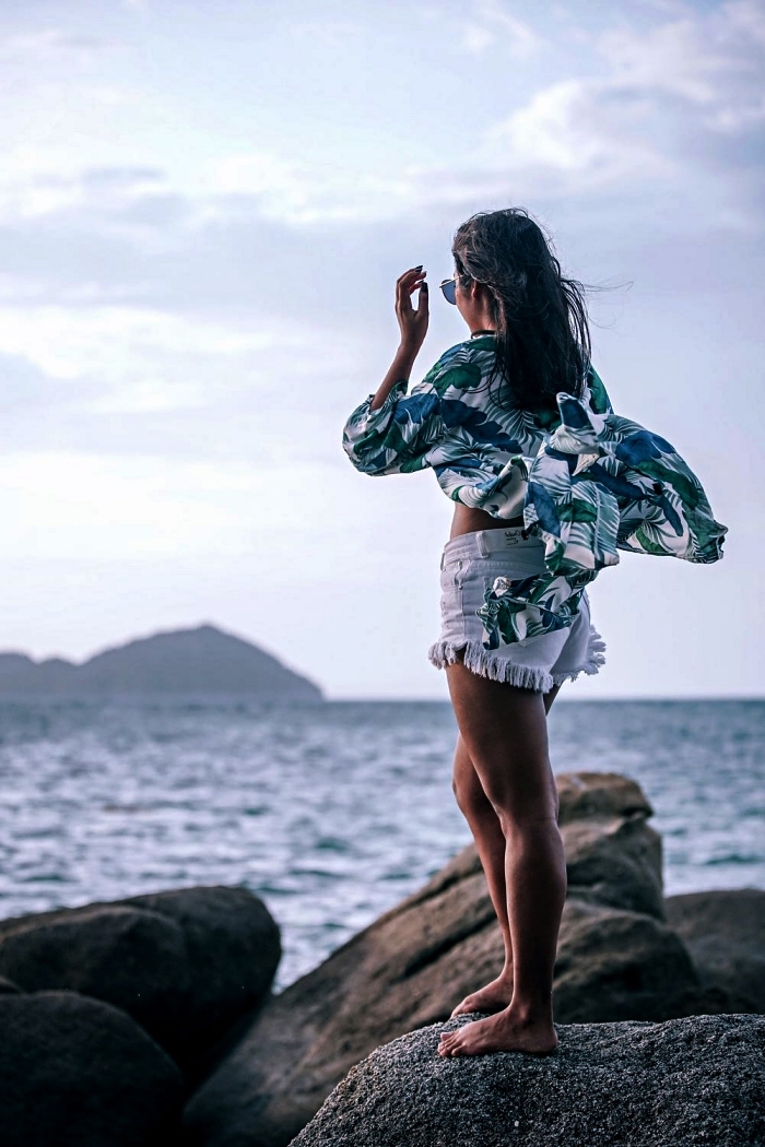 look de plage confortable en short denim blanc effiloché et kimono plage à imprimé tropical soulé par le vent