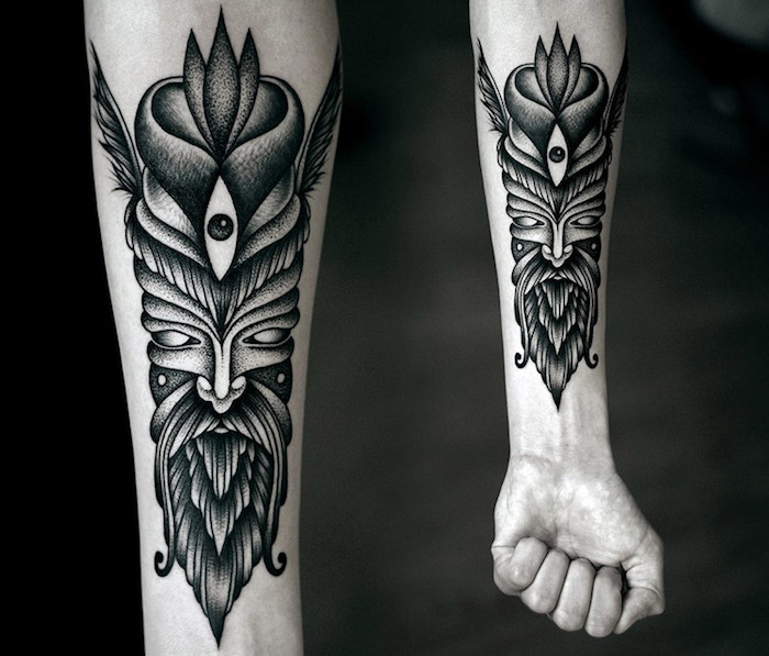 idée tête symbole tribal sur le bras en couleur noire, idée de masque tribal antique tatouée