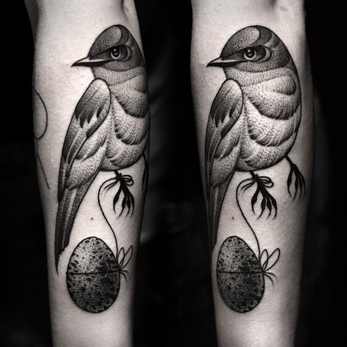 oeuf accroché au bout d un fil et oiseau gris graphique sur le bras, modele design de tatouage animalier