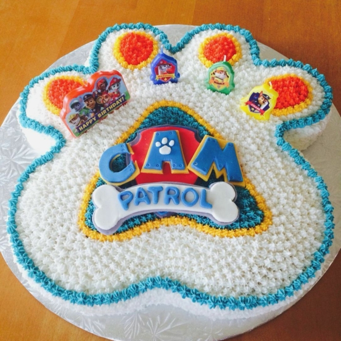 patte-patrouille-bougies-figurines-patte-patrouille-design-de-gateau-coloré-en-pate-à-modeler gateau patte patrouille en forme de patte de chien avec le logo du film, gâteau joliment décoré