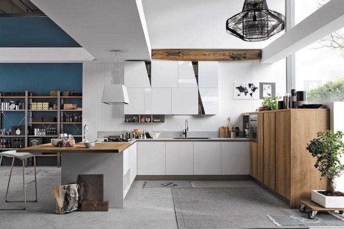 agencement cuisine moderne aux murs blancs avec accents en bois brut, déco cuisine ouverte vers un salon avec mur bleu