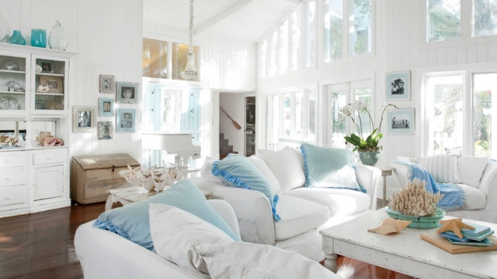 idée déco bord de mer dans un salon blanc à plafond haut avec plancher bois foncé, modèle de coussin bleu turquoise
