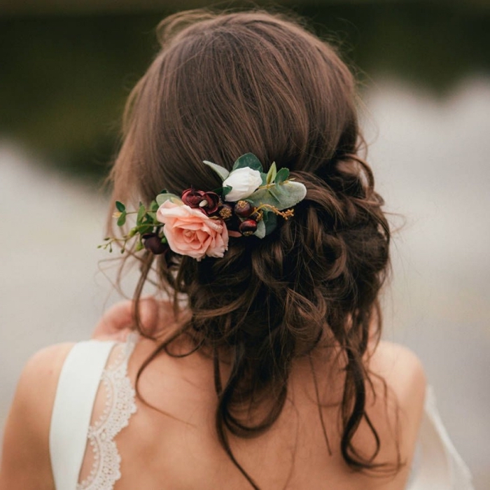 chignon mariee bas et flou avec boucles et accessoire fleuri, idée coiffure mariage pour cheveux longs attachés