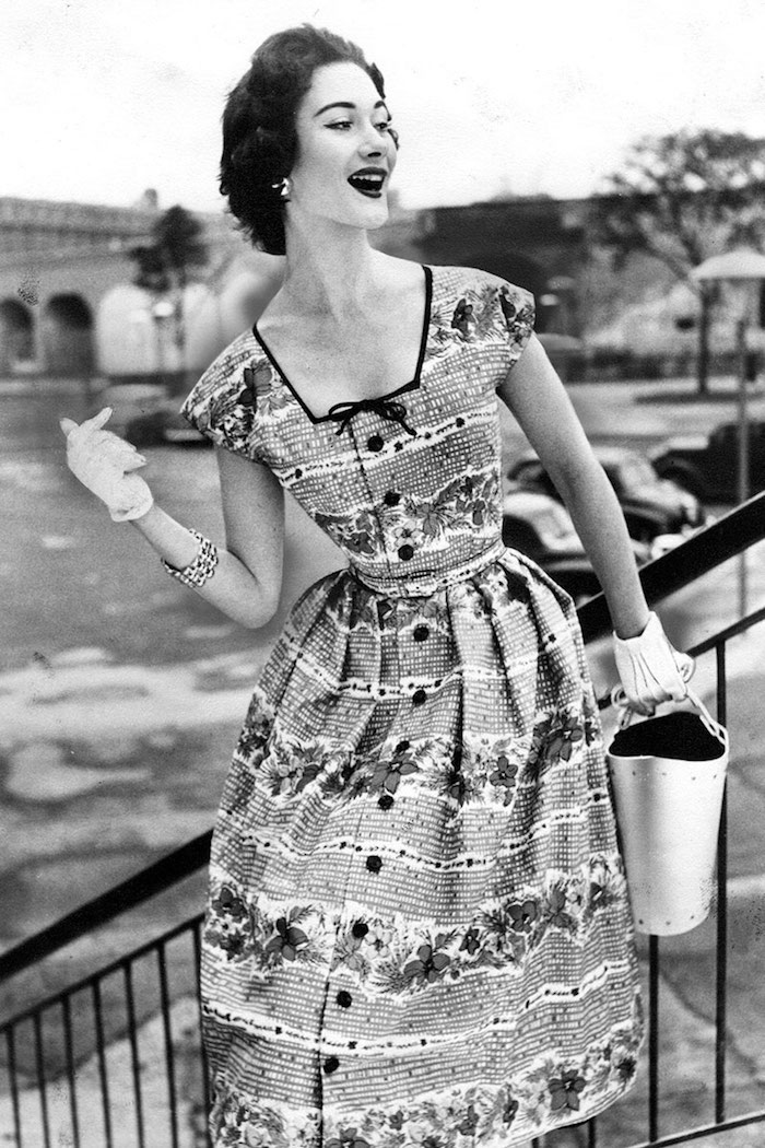 Femme souriante à la mode des annees 50, gants et grand montre, robe à boutons adorable