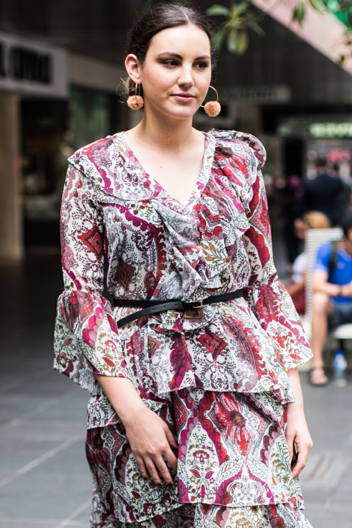 robe gris clair aux motifs rouges, créoles avec grands pompons beiges, chignon, ceinture en cuir