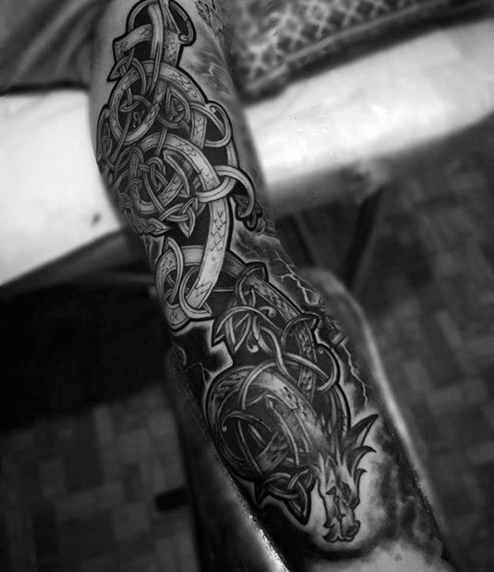 tatouage dragon macabre, corps d un dragon à l encre noire sur le bras d un homme