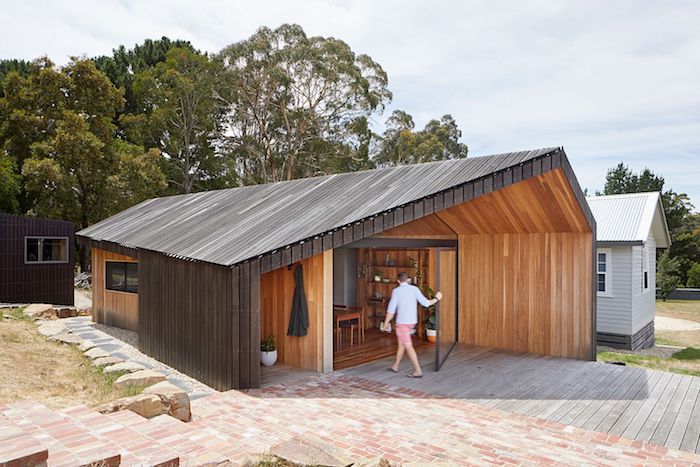grande extension bois originale style cottage avec une toiture en forme interessante sur une terrasse en bois