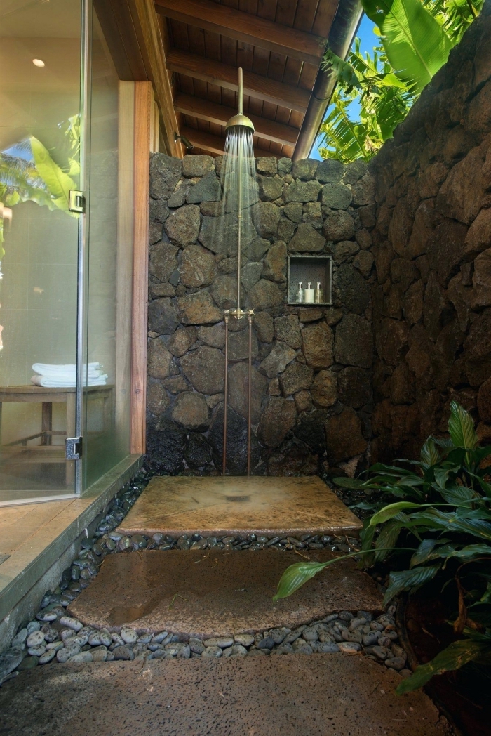 modèle de petite salle de bain zen aménagée dans le jardin avec murs en pierre et receveur de douche en pierre