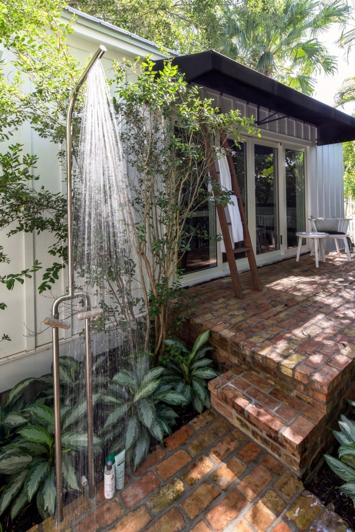 décoration de jardin avec revêtement de sol en briques et douche fixe en métal, idée aménagement terrasse en briques