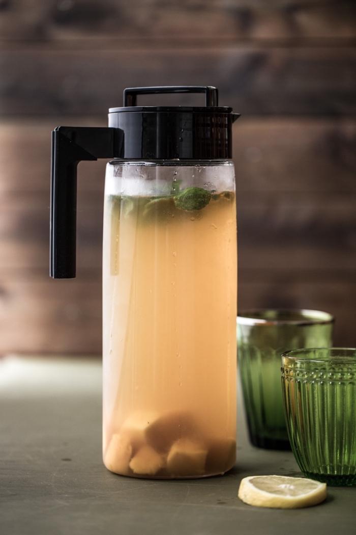 bouteille en verre remplie de thé vert refroidi aux fruits et feuilles de menthe, idée boisson froide saine aux fruits