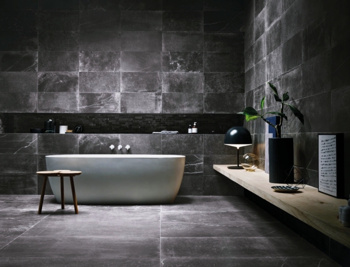 décoration salle de bain industriel aux murs et sol en gris anthracite avec baignoire blanche et étagère en bois clair