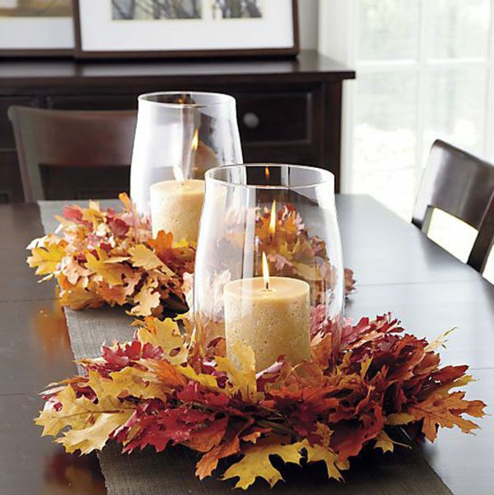 decoration de table chaleureuse, bougies allumées, feuilles d'automne arrangées, bougeoirs en verre simples