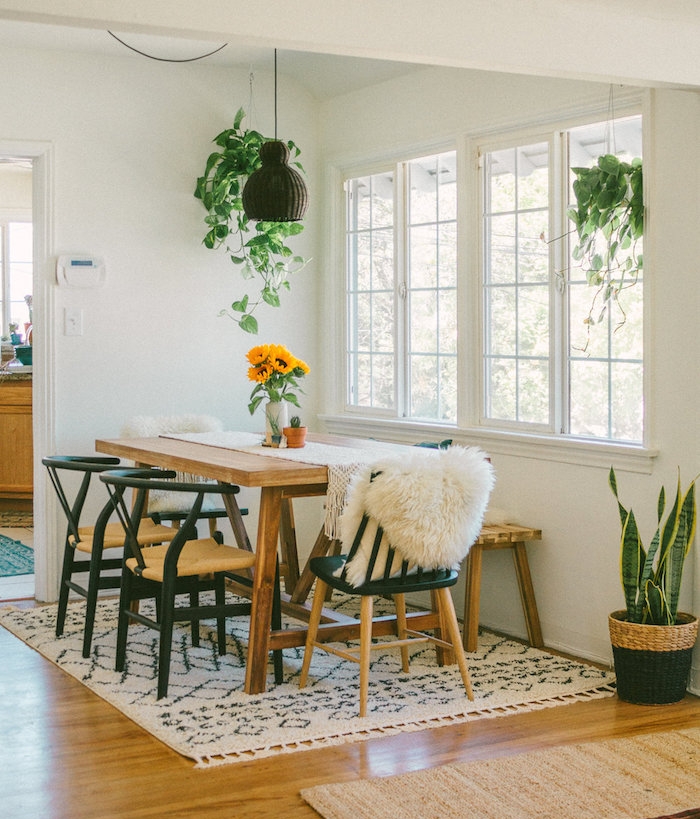 salle à manger contemporaine avec table bois brut, chaises bois et métal et tapis noir et blanc, sansevière en cache pot tressé et pots de plantes retombantes