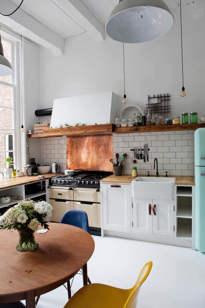 Cool petite cuisine avec coin table ronde chaises rétro à couleurs vintages, grande lustre, vase avec fleurs, aménagement cuisine petit appartement