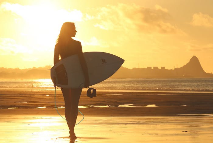 Fille surfeur sur la plage avec son surf au coucher de soleil, fond d écran paysage, découvrir la beauté de notre monde